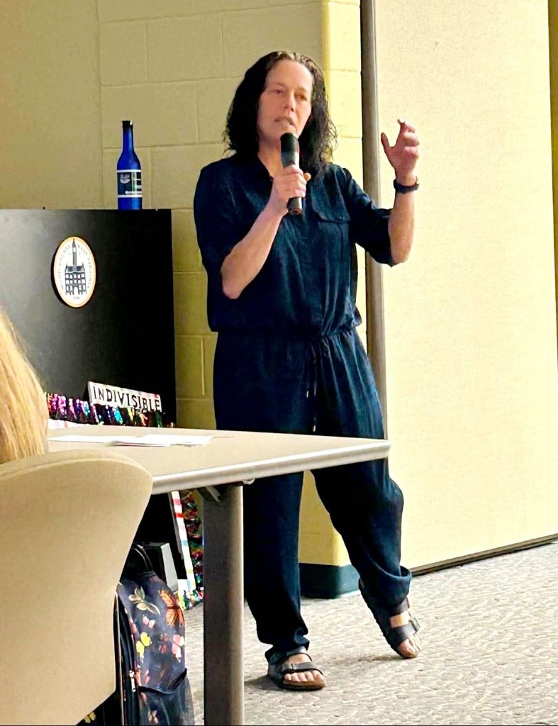 Crystal Butcher addressing a crowd with conviction, holding a microphone and gesturing with purpose