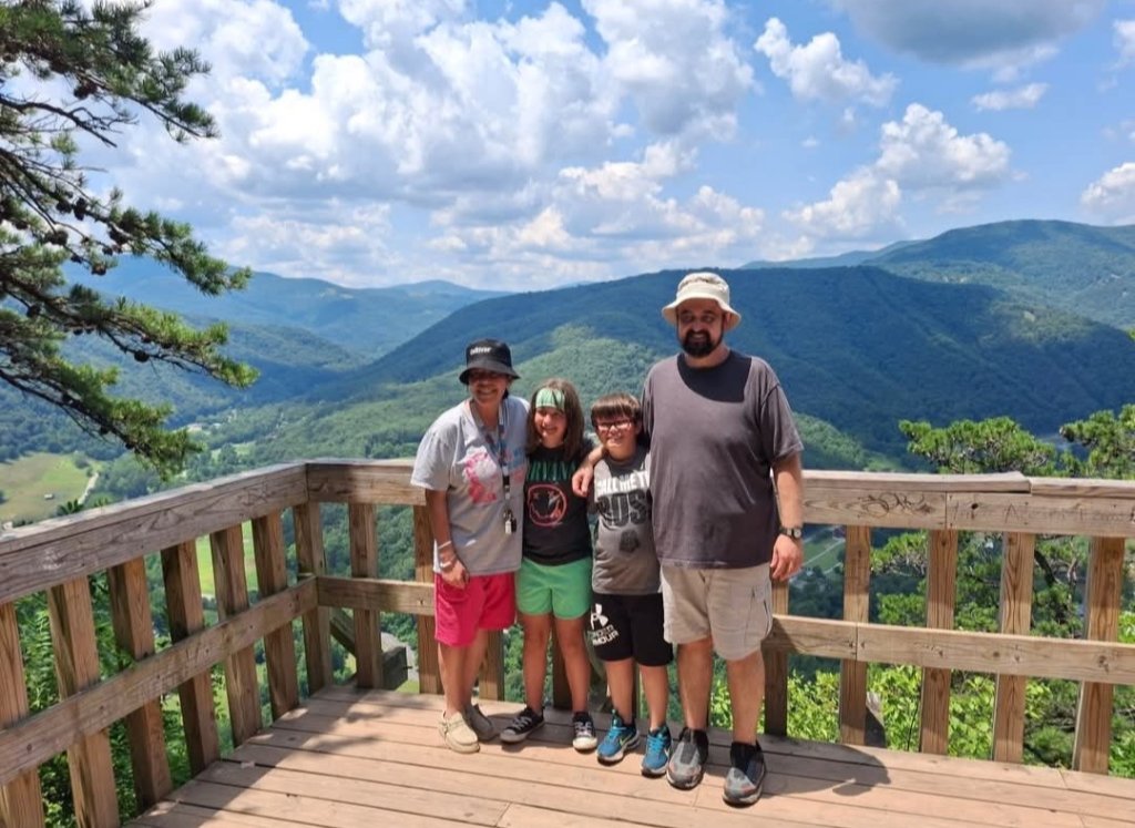 Crystal Butcher and her family on a wooden observation deck overlooking the rolling green mountains of West Virginia