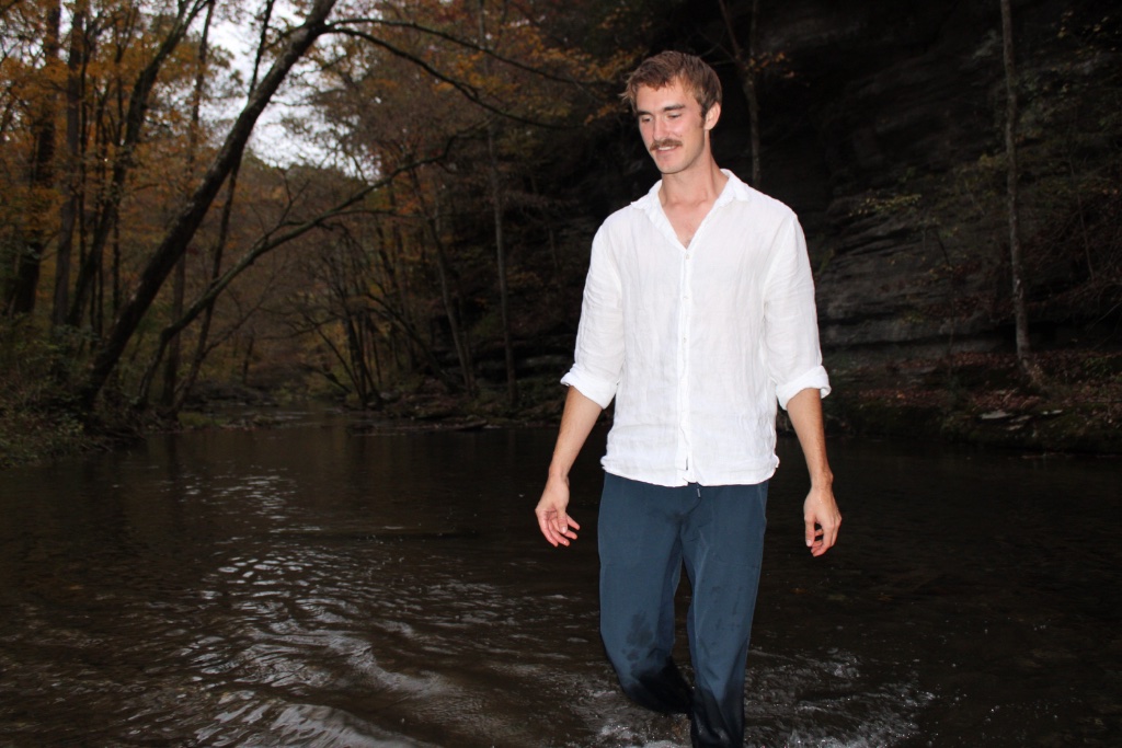 Matthew Shield wading through a forest stream