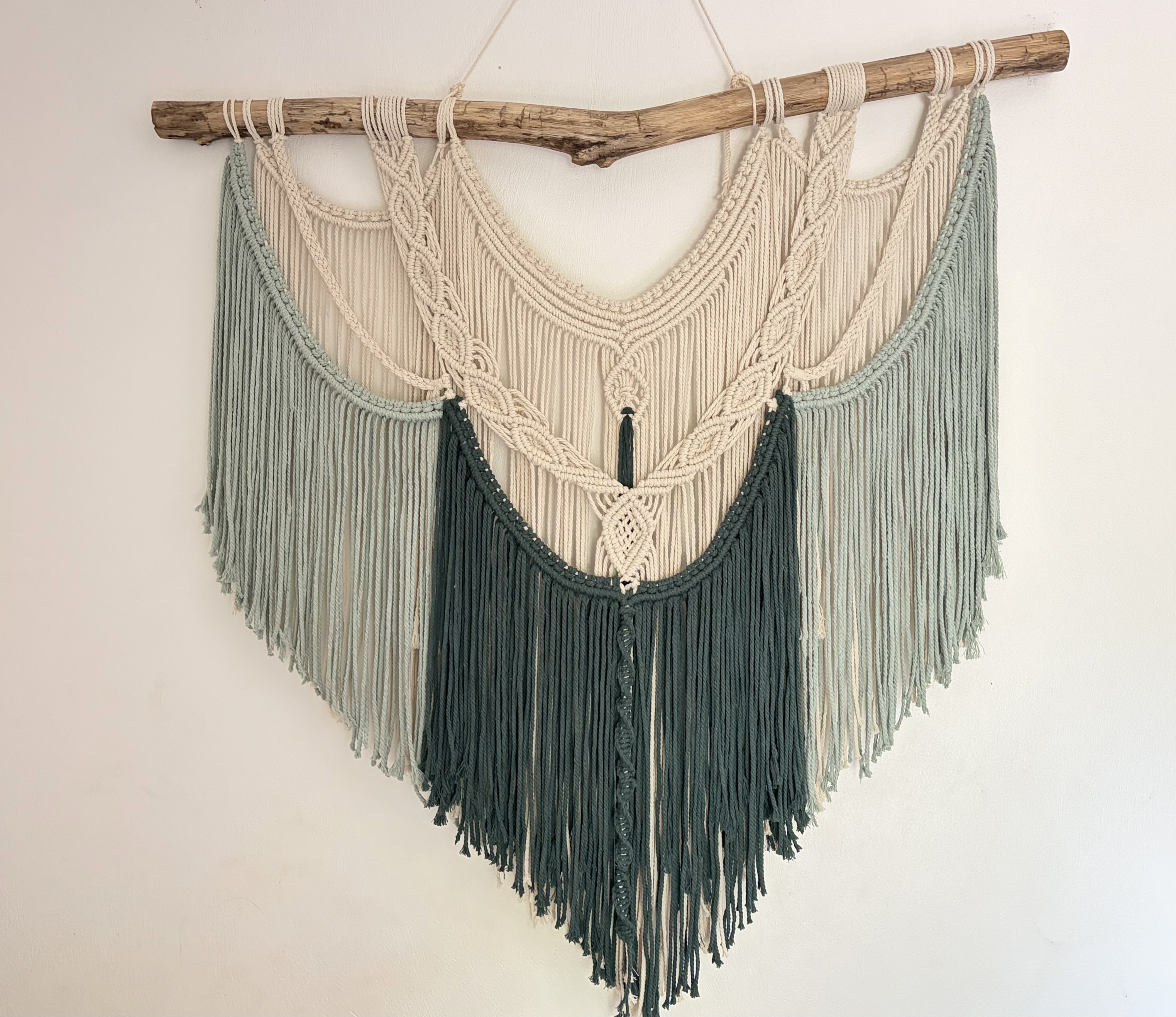 Macramé wall hanging in sage and forest green on driftwood