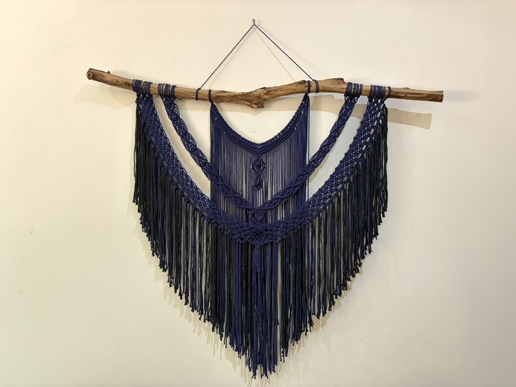 Dark blue macramé wall hanging on driftwood