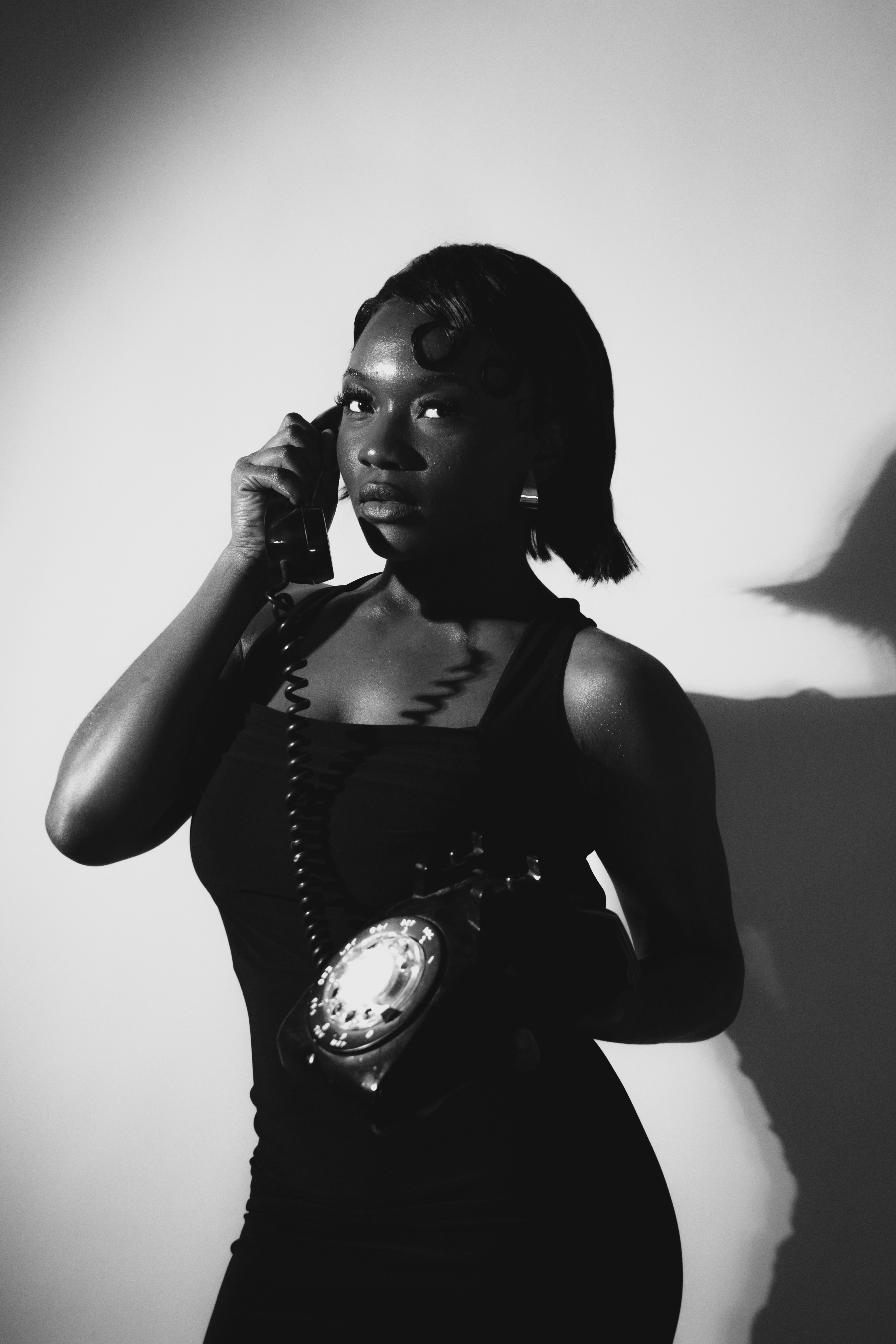 Black and white editorial portrait, woman on vintage telephone