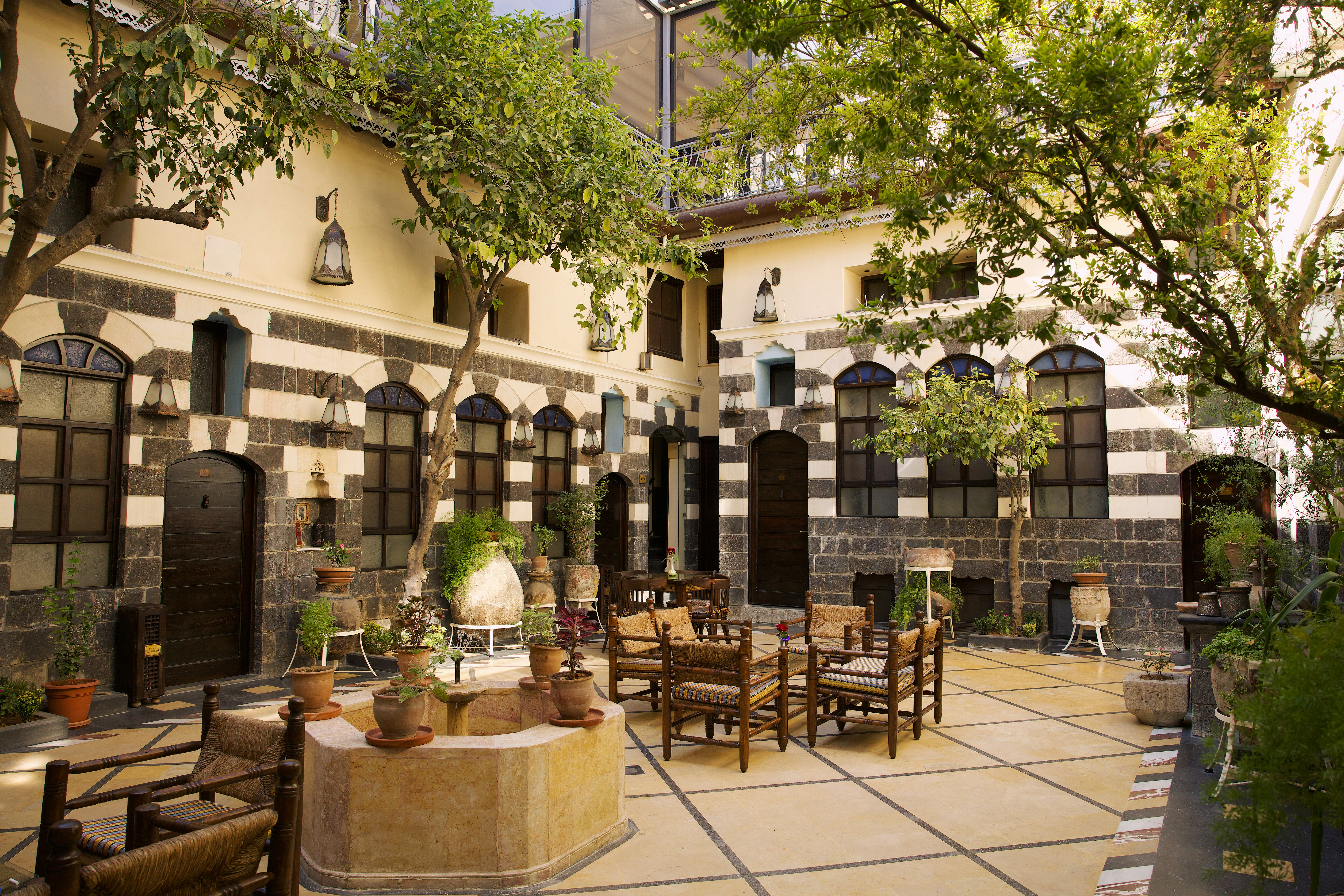 Sunlight streaming through a stone arch in the courtyard of Beit Ramza Hotel