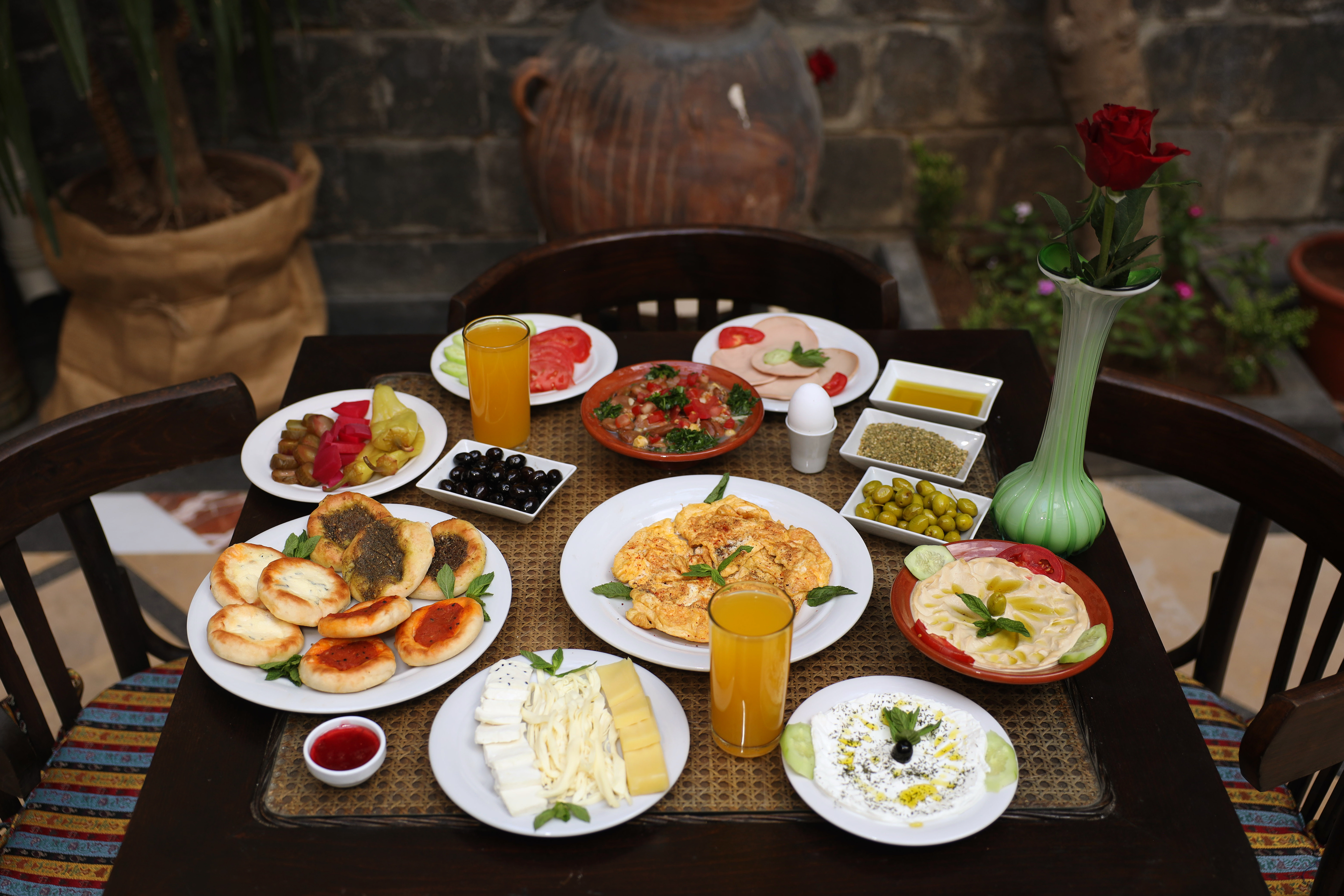 A traditional Syrian breakfast spread on a dark wood table in the Beit Ramza courtyard
