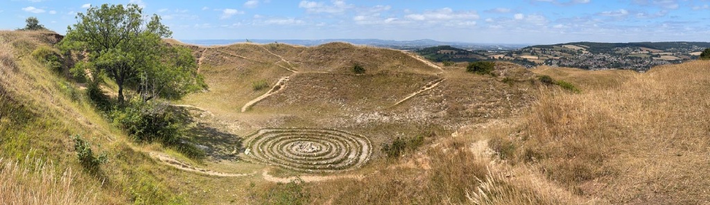 A large stone spiral labyrinth on a grassy hillside