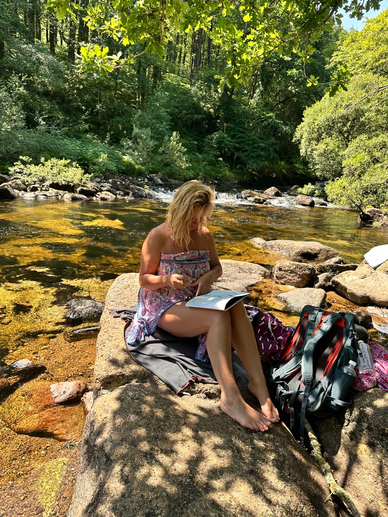 A woman writing on a rock in a flowing river