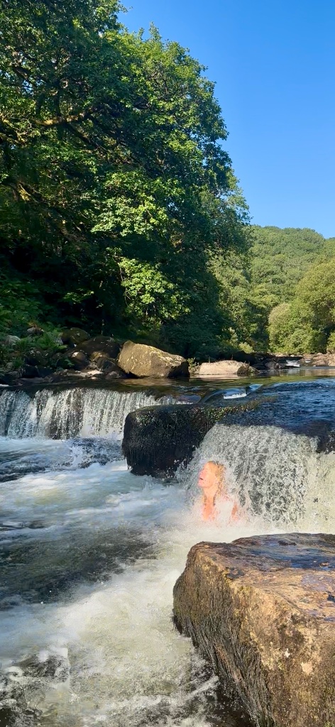 Bathing in the river beneath a small waterfall
