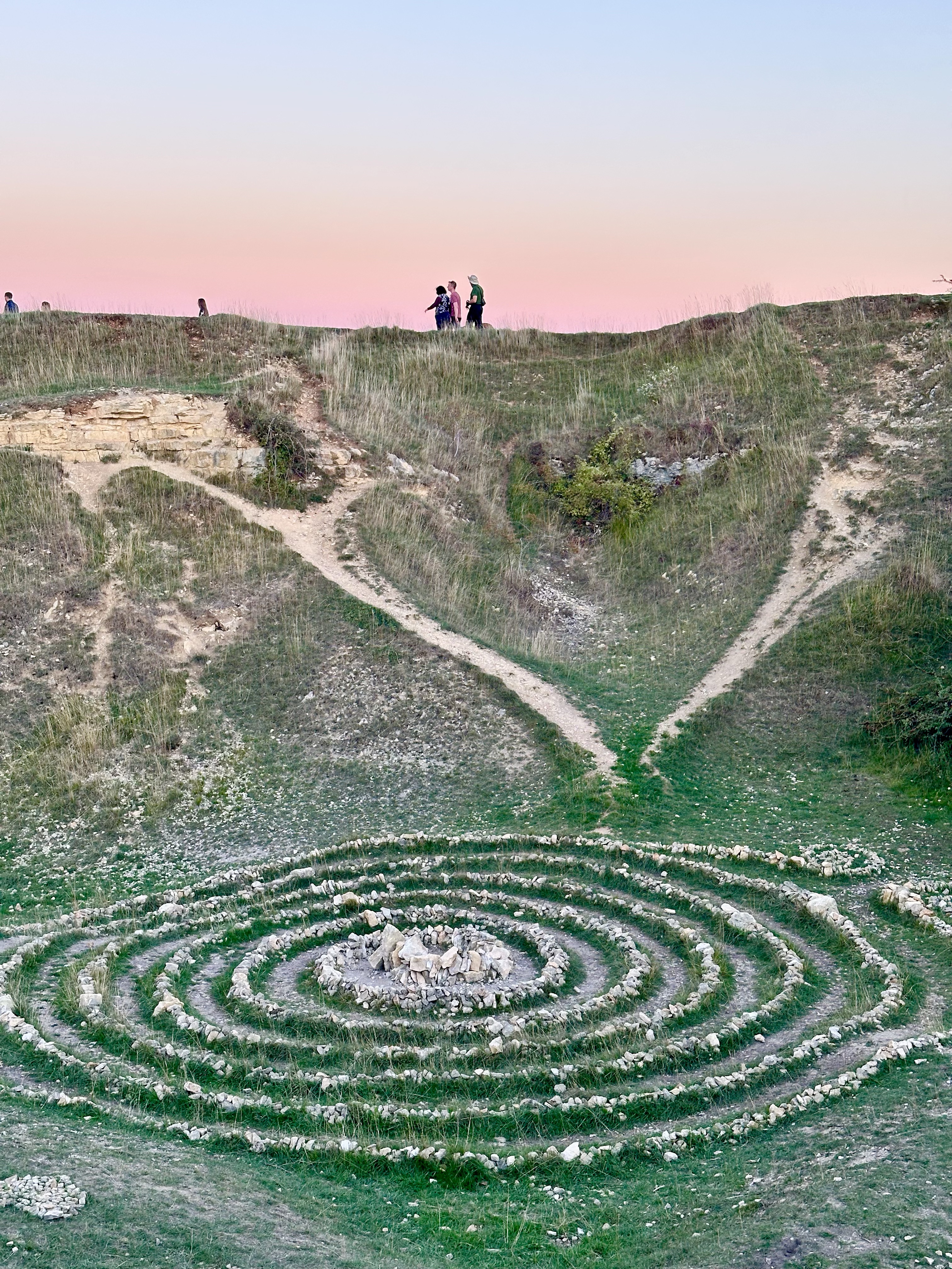 A stone spiral in a grassy hollow at dusk