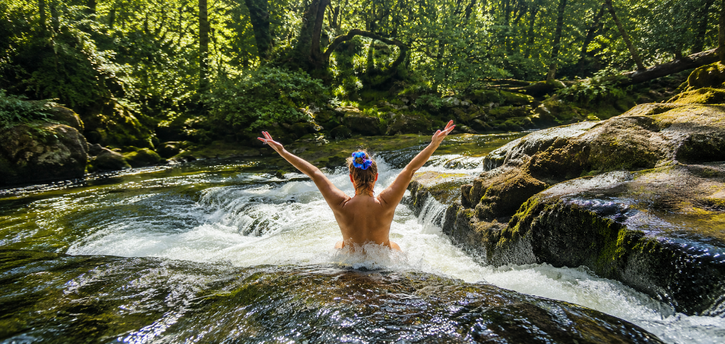 Vittoria Immortelle standing in a forest stream with arms raised
