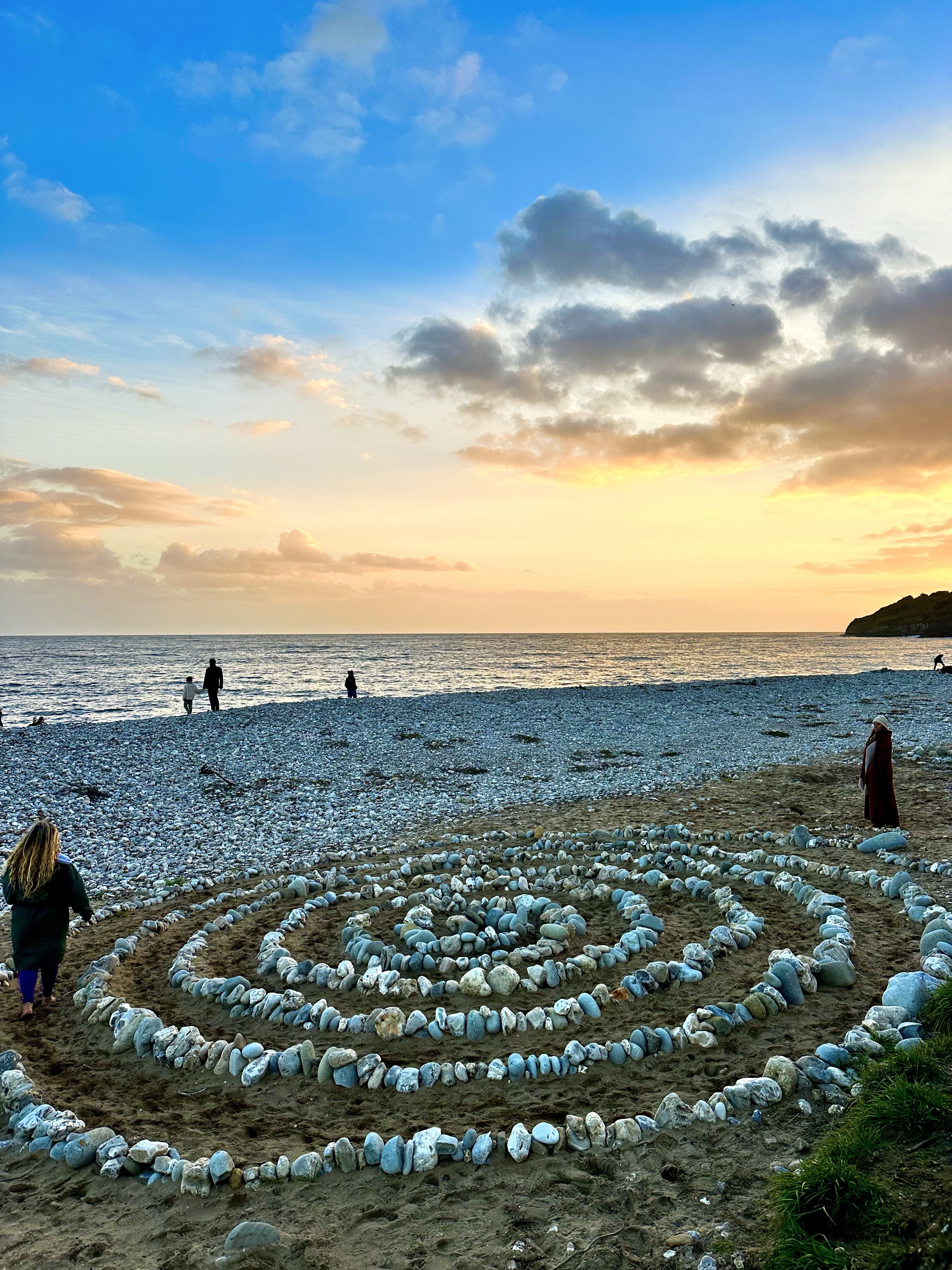A stone spiral laid on the sand at sunset