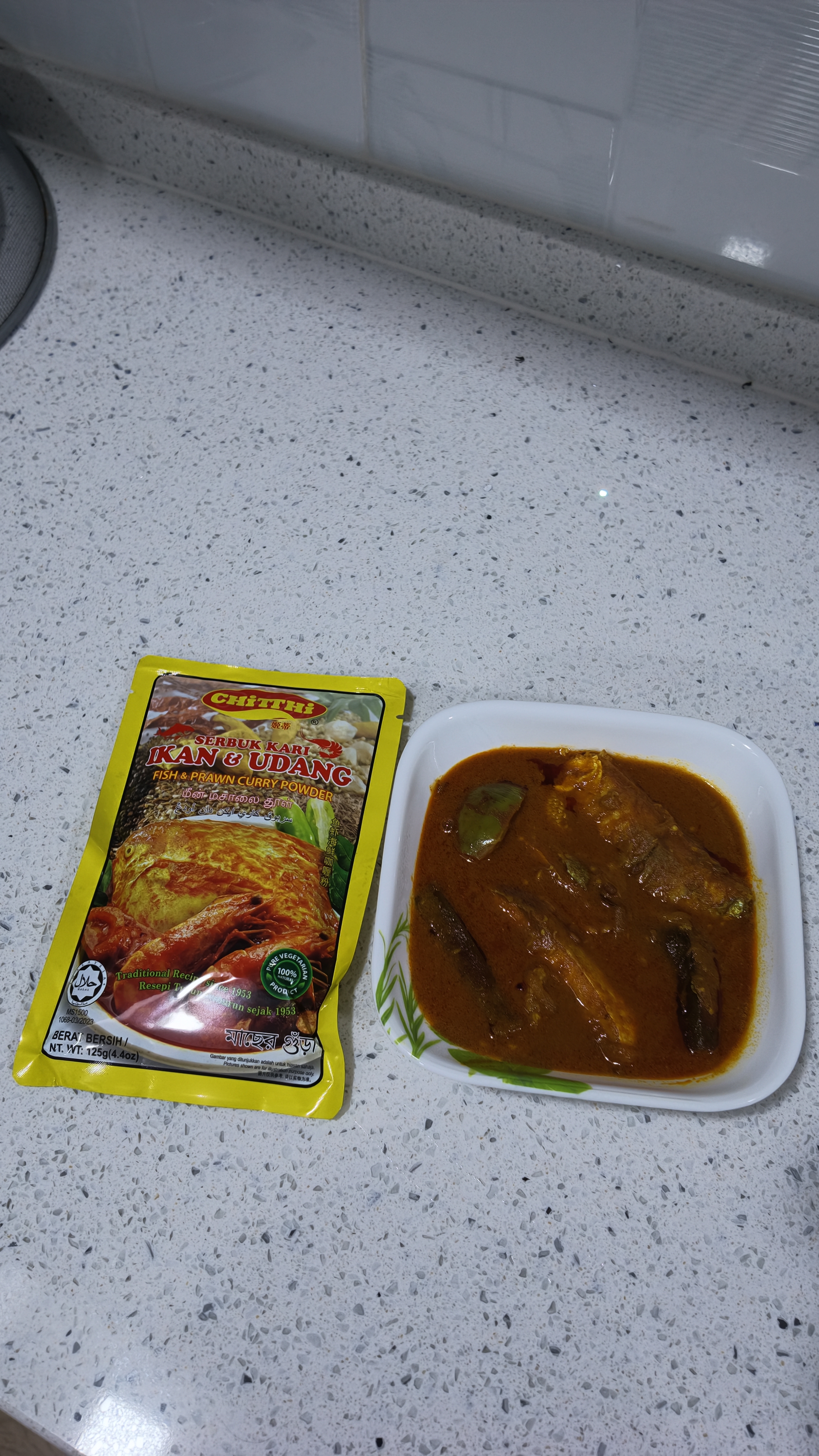 Chitthi fish & prawn curry powder beside a bowl of fish curry