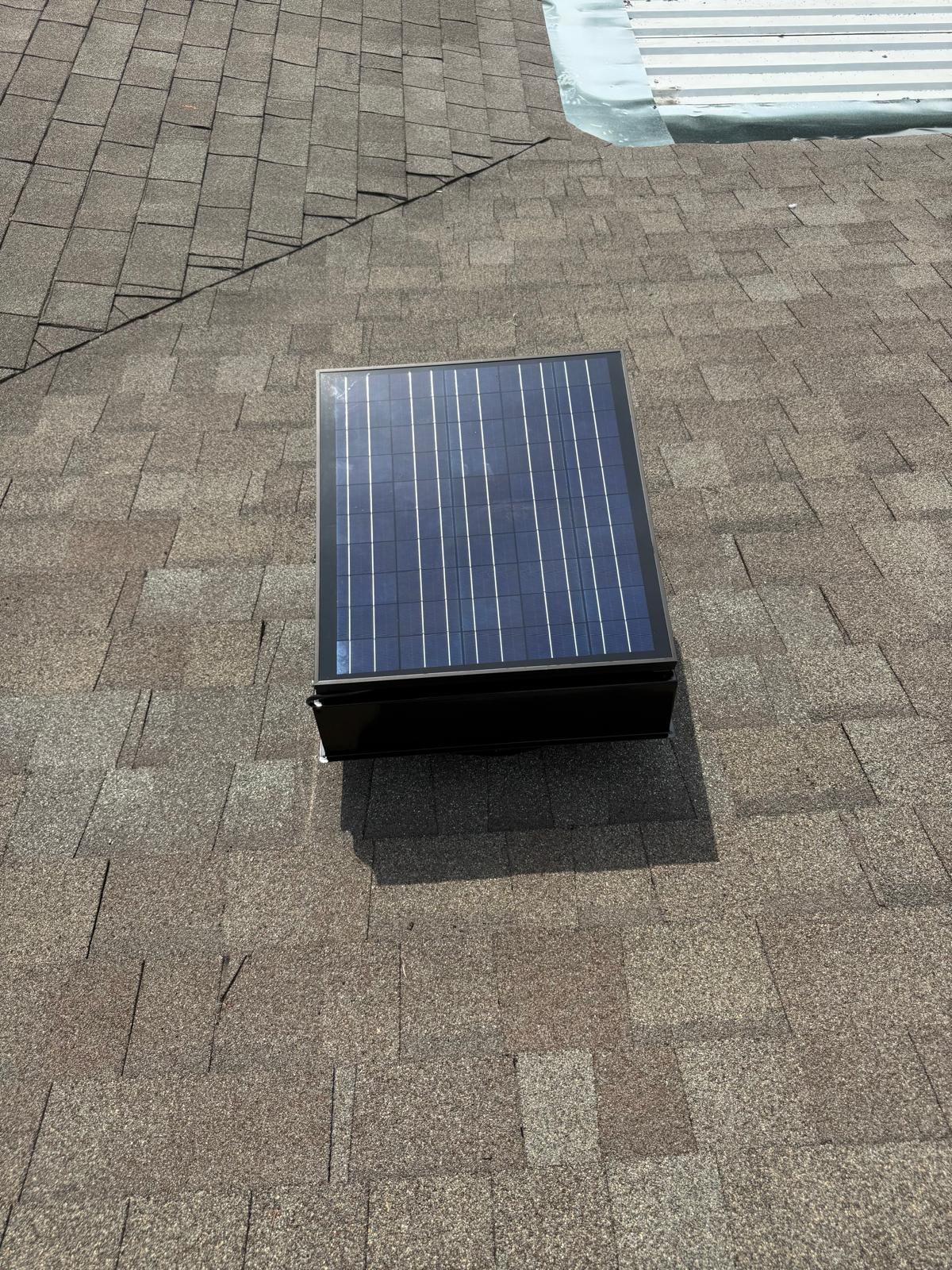 Close-up of the solar panel attached to the top of a roof attic vent fan