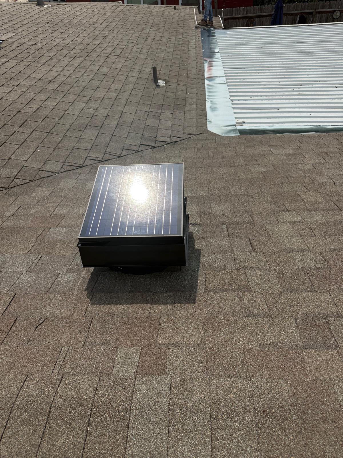Solar attic vent unit mounted on a residential asphalt shingle roof
