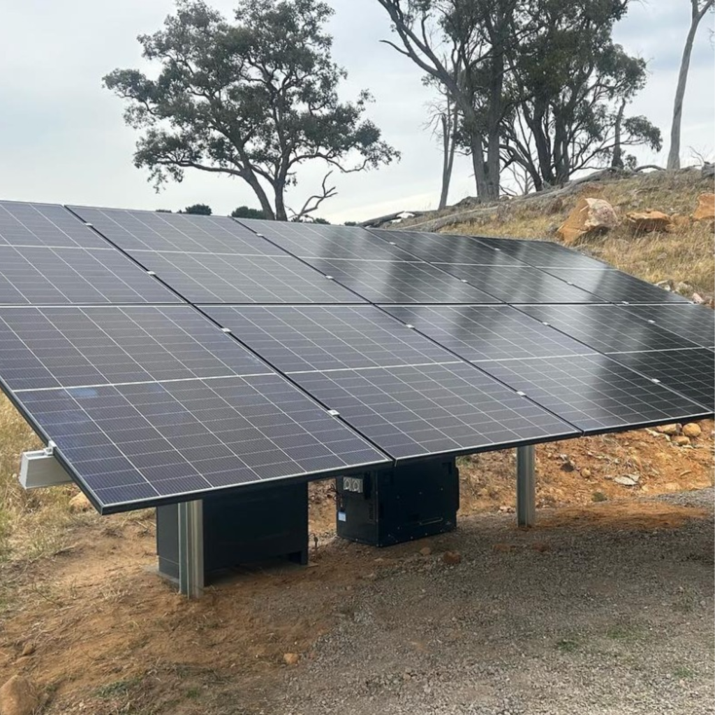 Ground-mounted off-grid solar panel array in a rural Australian landscape.
