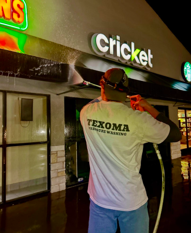 Commercial Pressure Washing Texoma Texoma Pressure Washing technician pressure washing a commercial storefront in Sherman TX at night