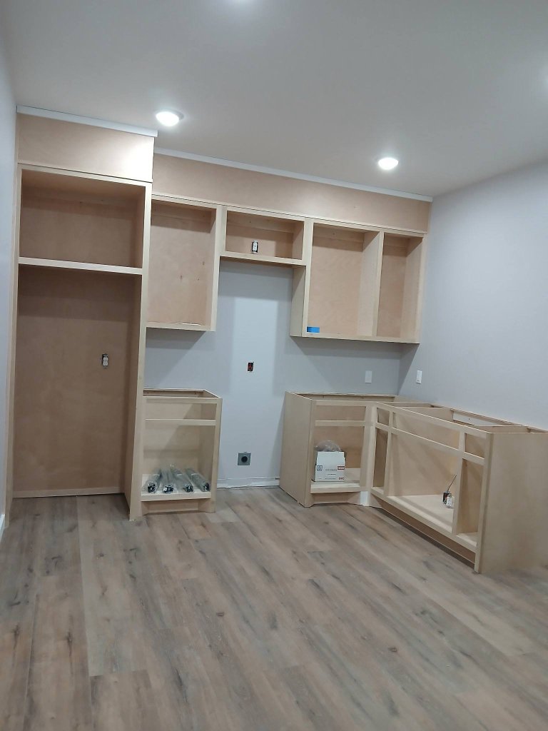 Kitchen installation in progress with unfinished light oak cabinetry and a tall pantry enclosure in a Celina home