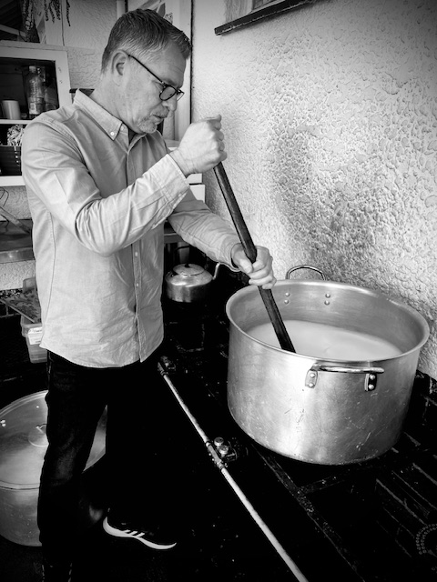A volunteer stirring a large community food pot