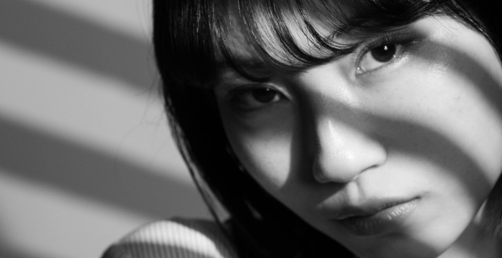 A high-contrast black and white portrait showing detailed skin texture and dramatic side-shadowing