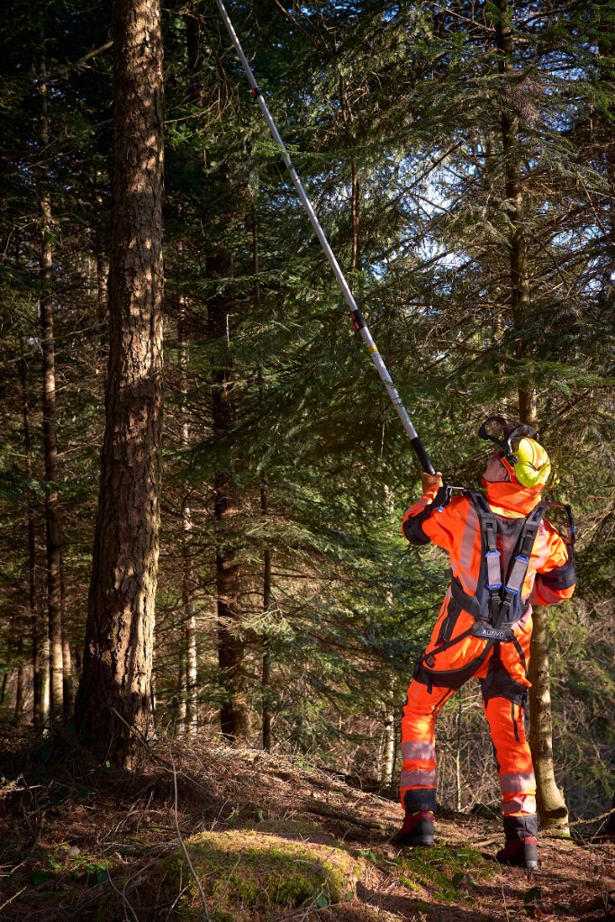 Boswerker met exoskelet bij snoeiwerk op een steile helling