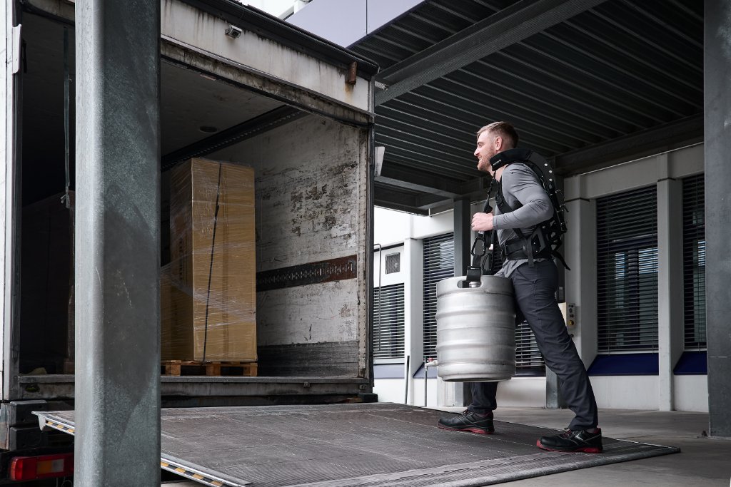Medewerker draagt een biervat met de CarrySuit op een laadperron, gezien van achteren
