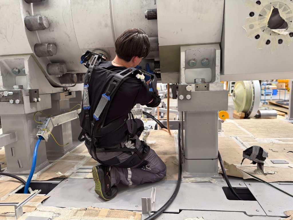 Monteur knielend aan machine met OmniSuit