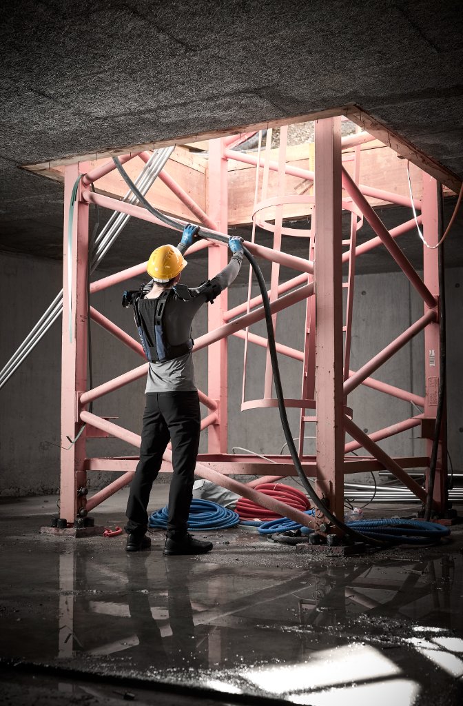 Monteur met DeltaSuit reikt omhoog met kabel