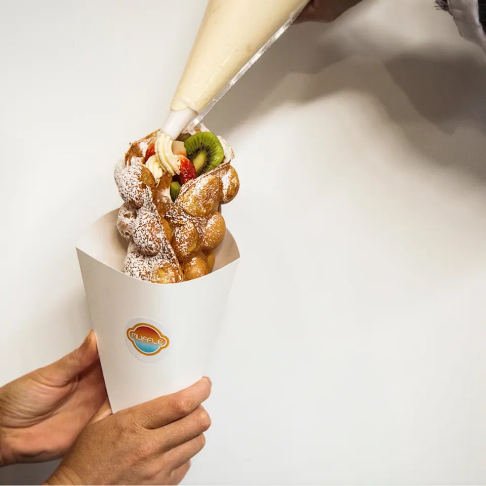 Whipped cream being piped onto a Muffle