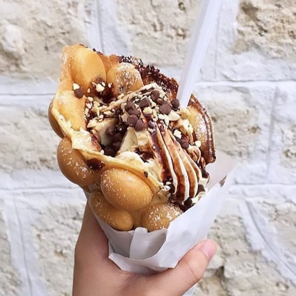 A handheld Muffle filled with ice cream, chocolate chips and chocolate sauce