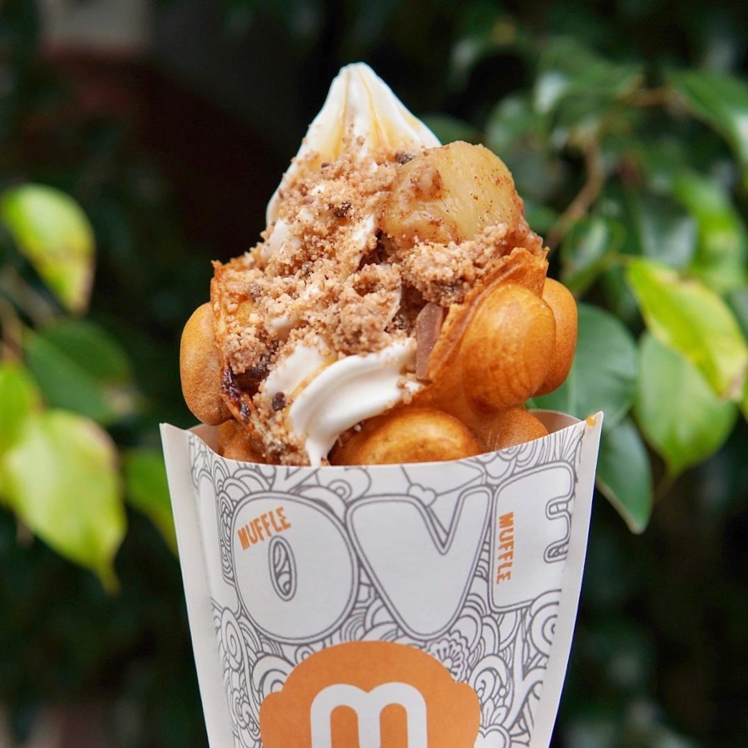 A golden Muffle loaded with soft-serve ice cream, banana slices and biscuit crumble