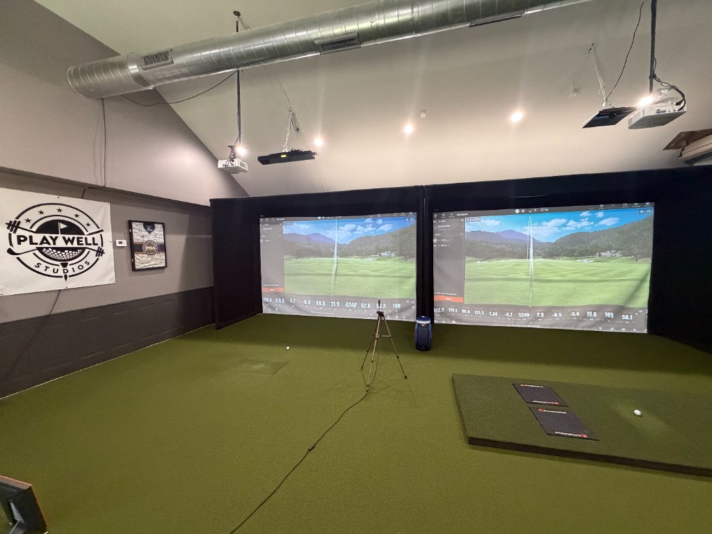 Interior of the Play Well Studios indoor golf facility with simulator bays
