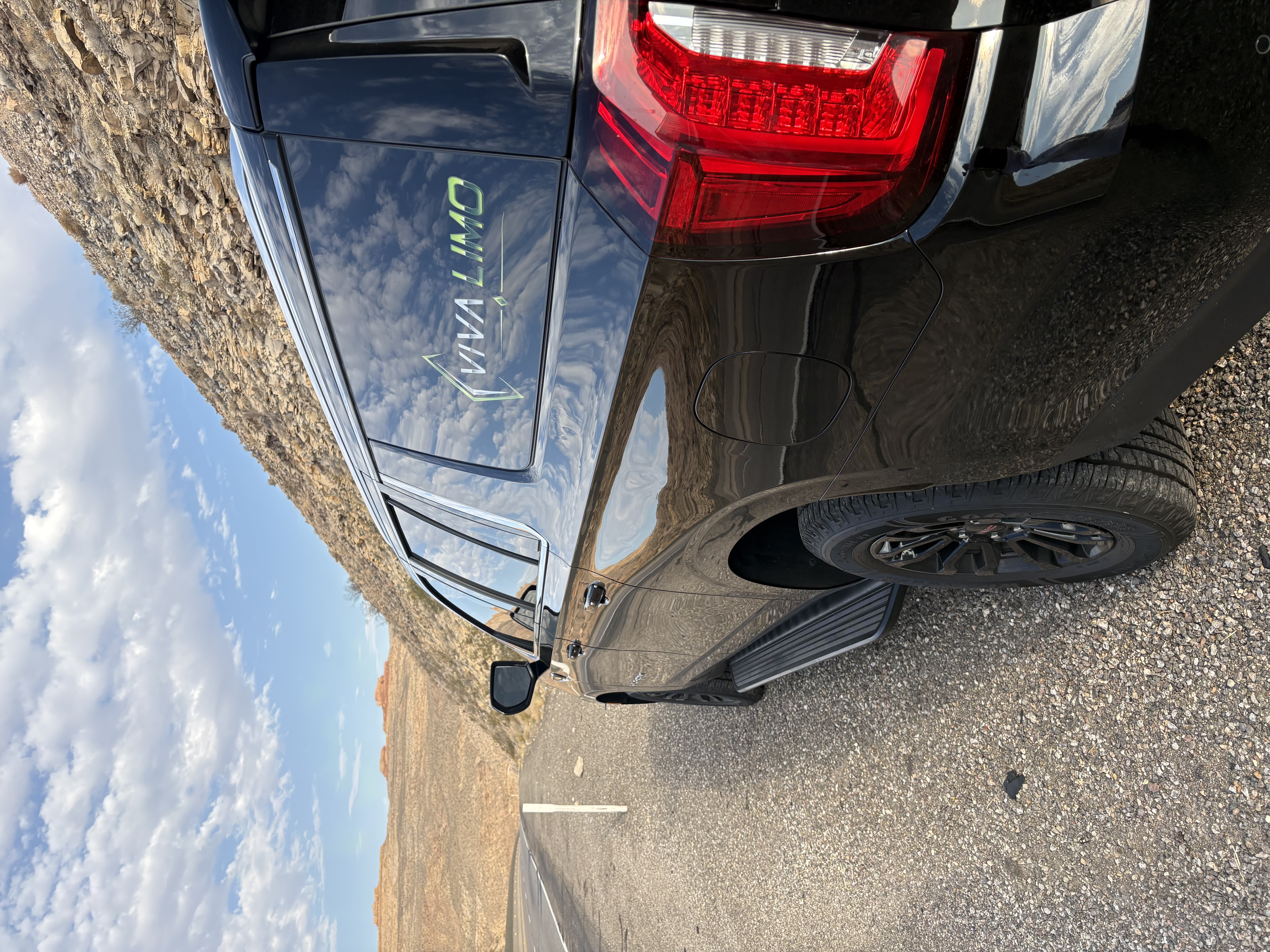 Black Viva Limo SUV rear three-quarter view in the Las Vegas desert mountains