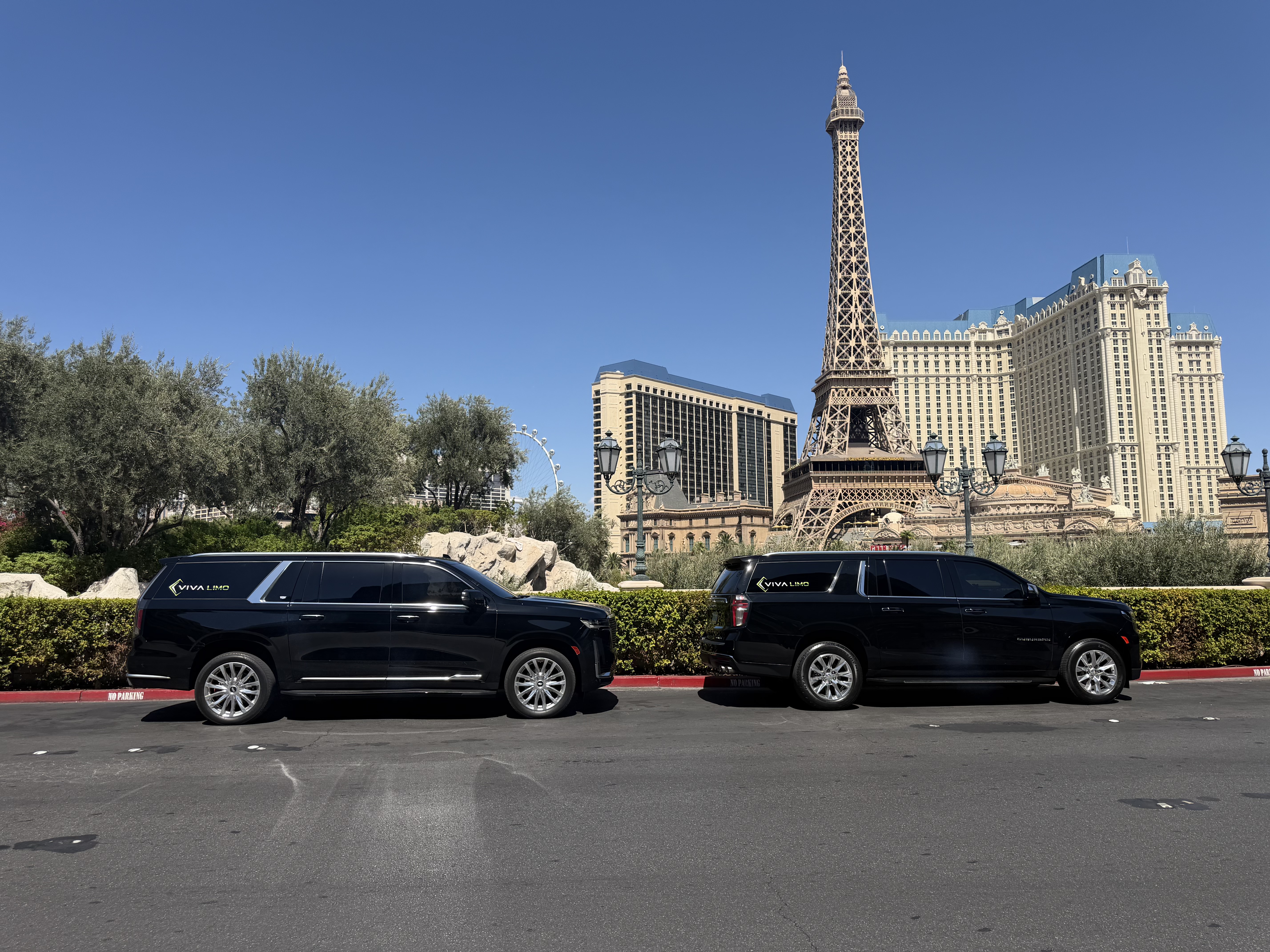 Two black Viva Limo branded SUVs parked side by side in front of the Paris Las Vegas Eiffel Tower