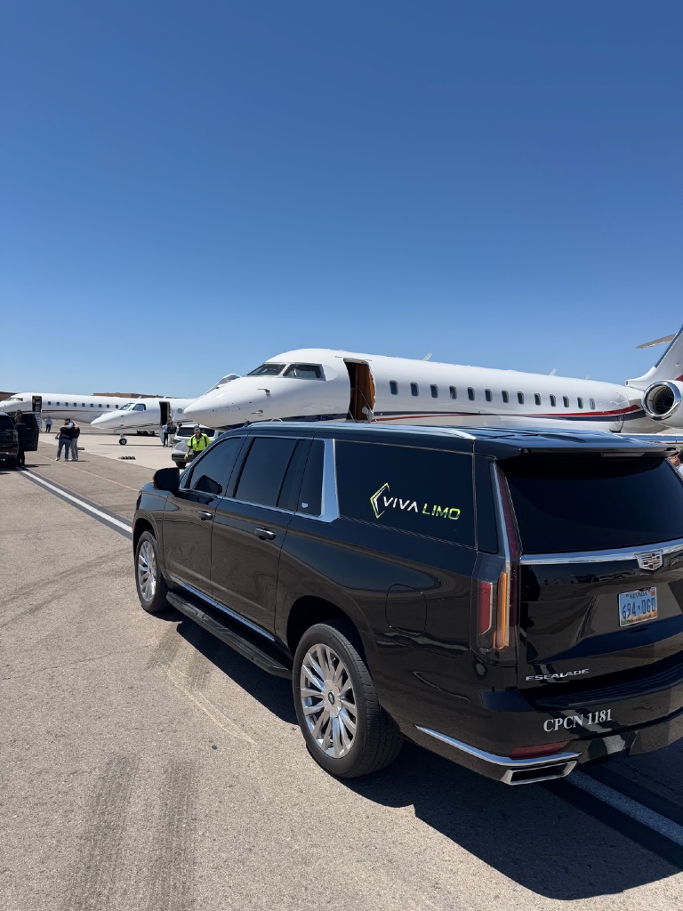 Black Cadillac Escalade on an airport tarmac beside private jets