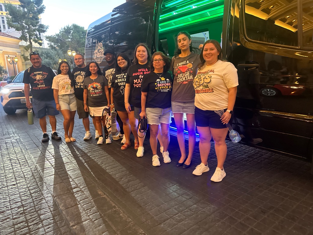 Group of ten posing in front of a black Mercedes Sprinter van with green interior LED lighting in Las Vegas