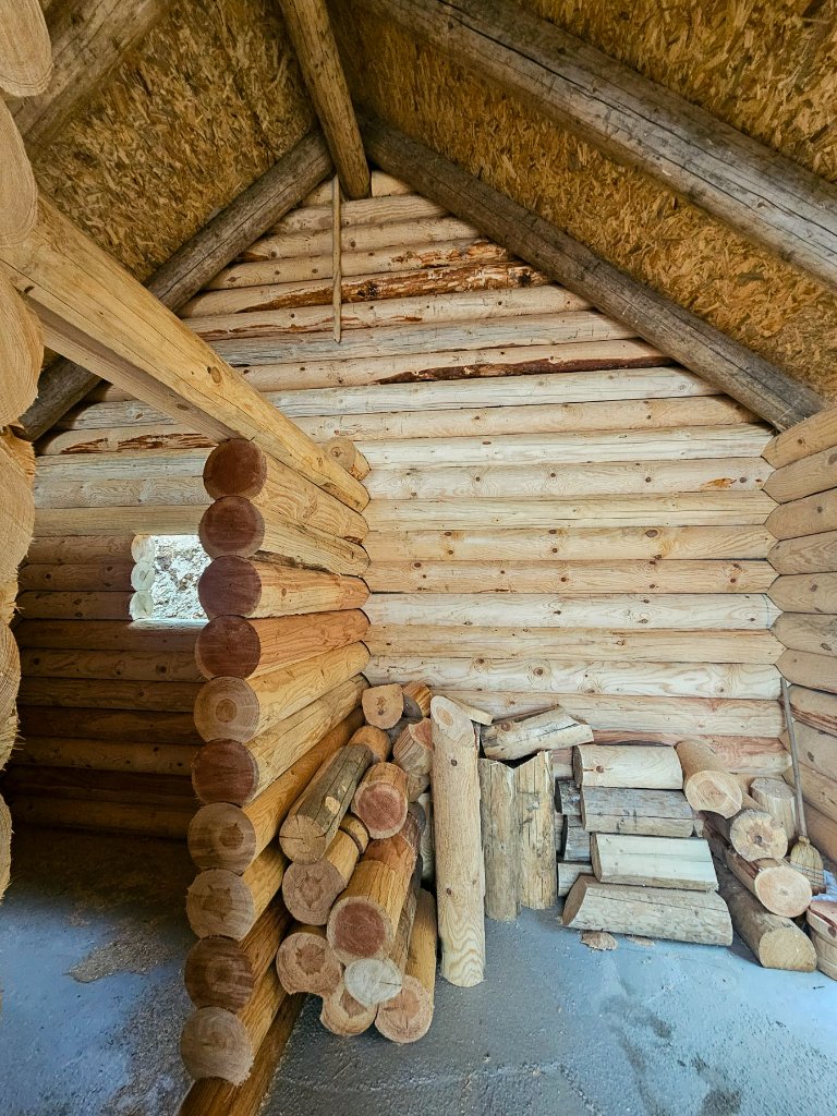 Unutrašnjost brvnare sa otvorenim vratima — početna faza