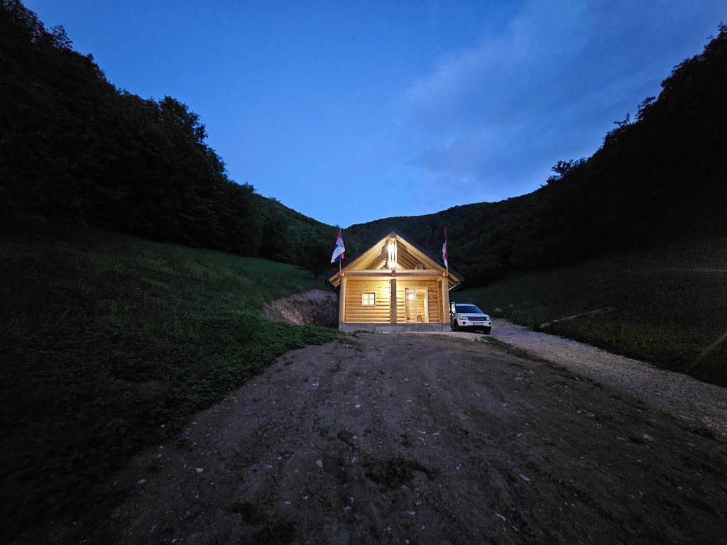 Završena brvnara u sumrak sa toplom unutrašnjom rasvetom