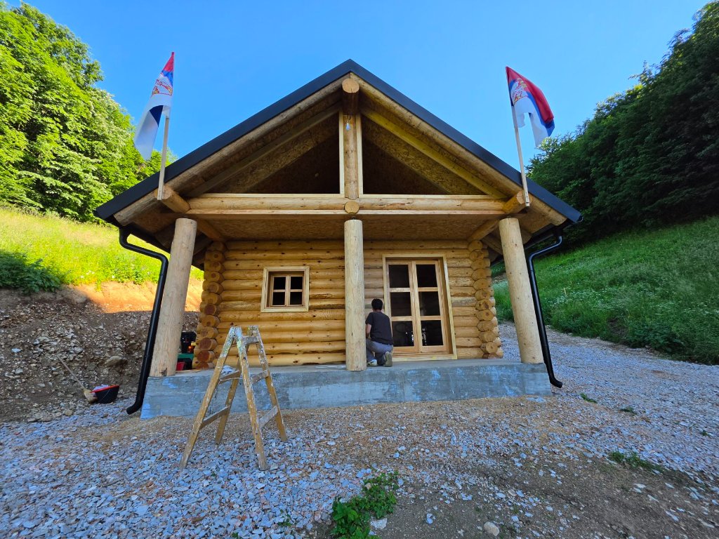 Podignuta drvena konstrukcija brvnare sa krovom — radnici na objektu