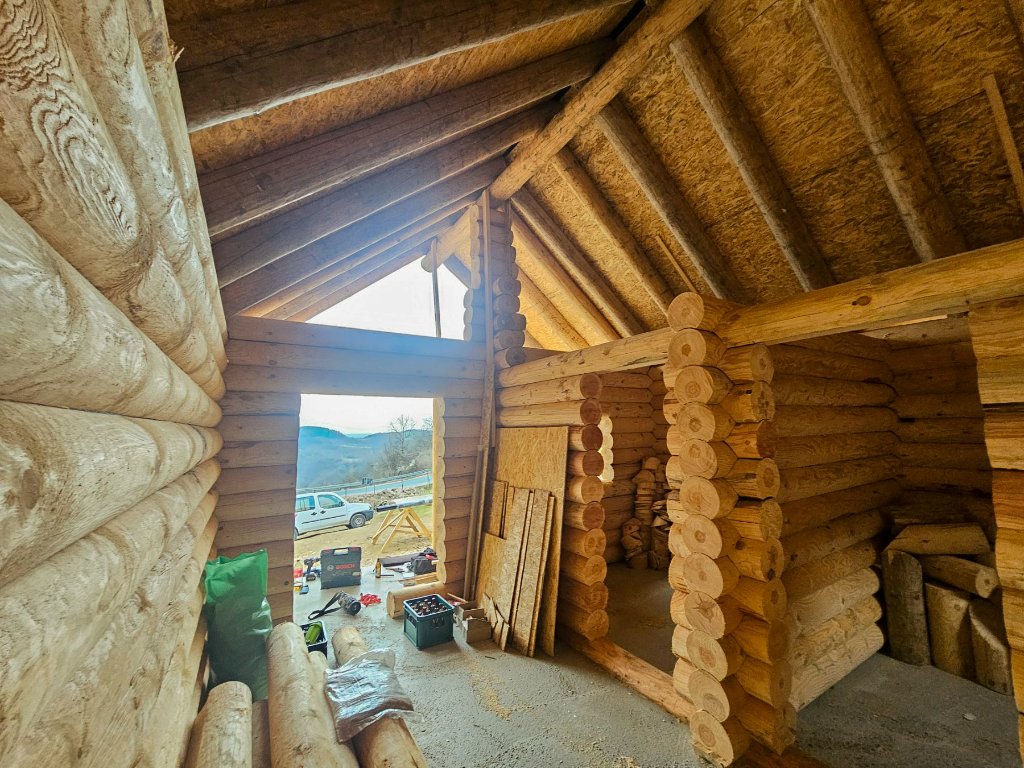 Unutrašnjost sa skladištenim brvnima i alatom — početak radova