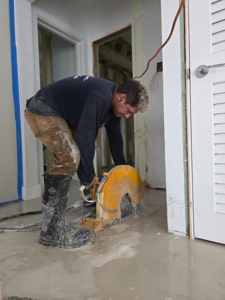 Handheld concrete saw cutting a wet floor on a South Florida job site