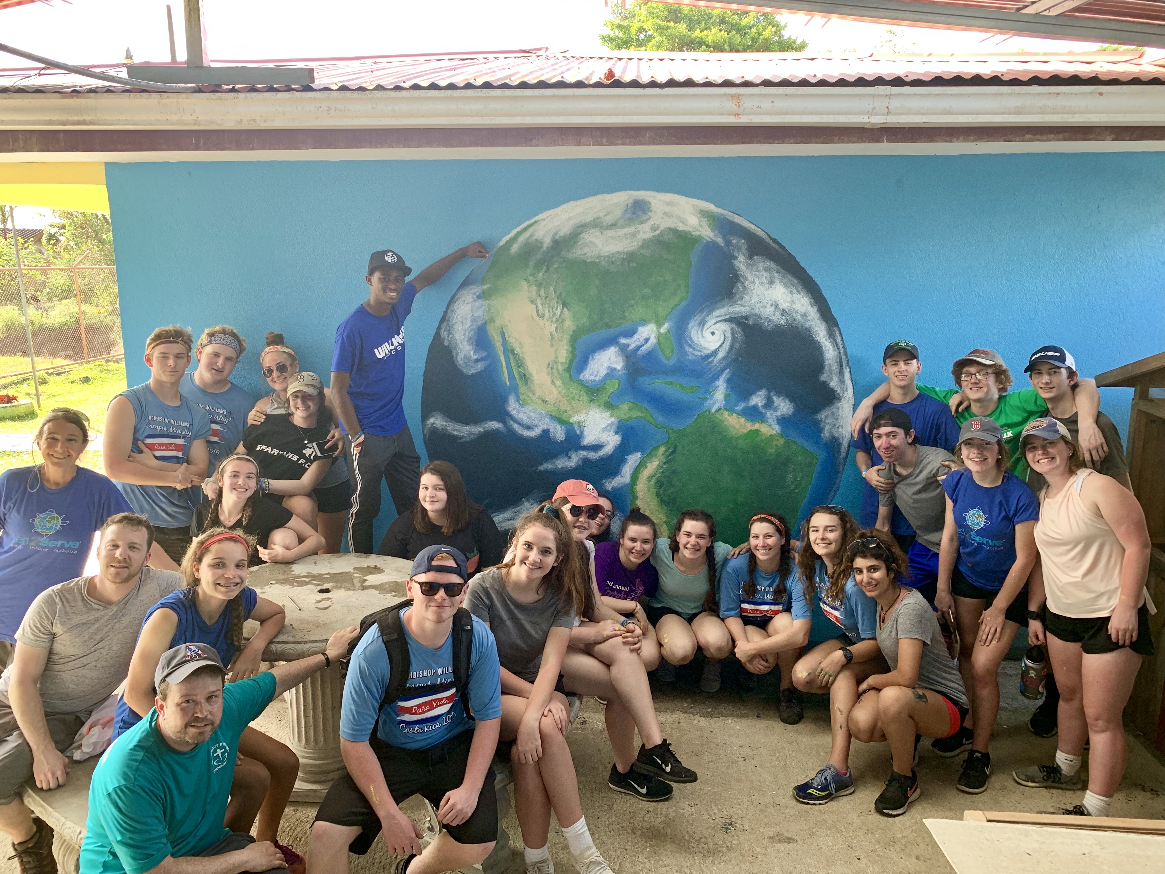 Led2Serve volunteer group posing in front of a painted Earth mural