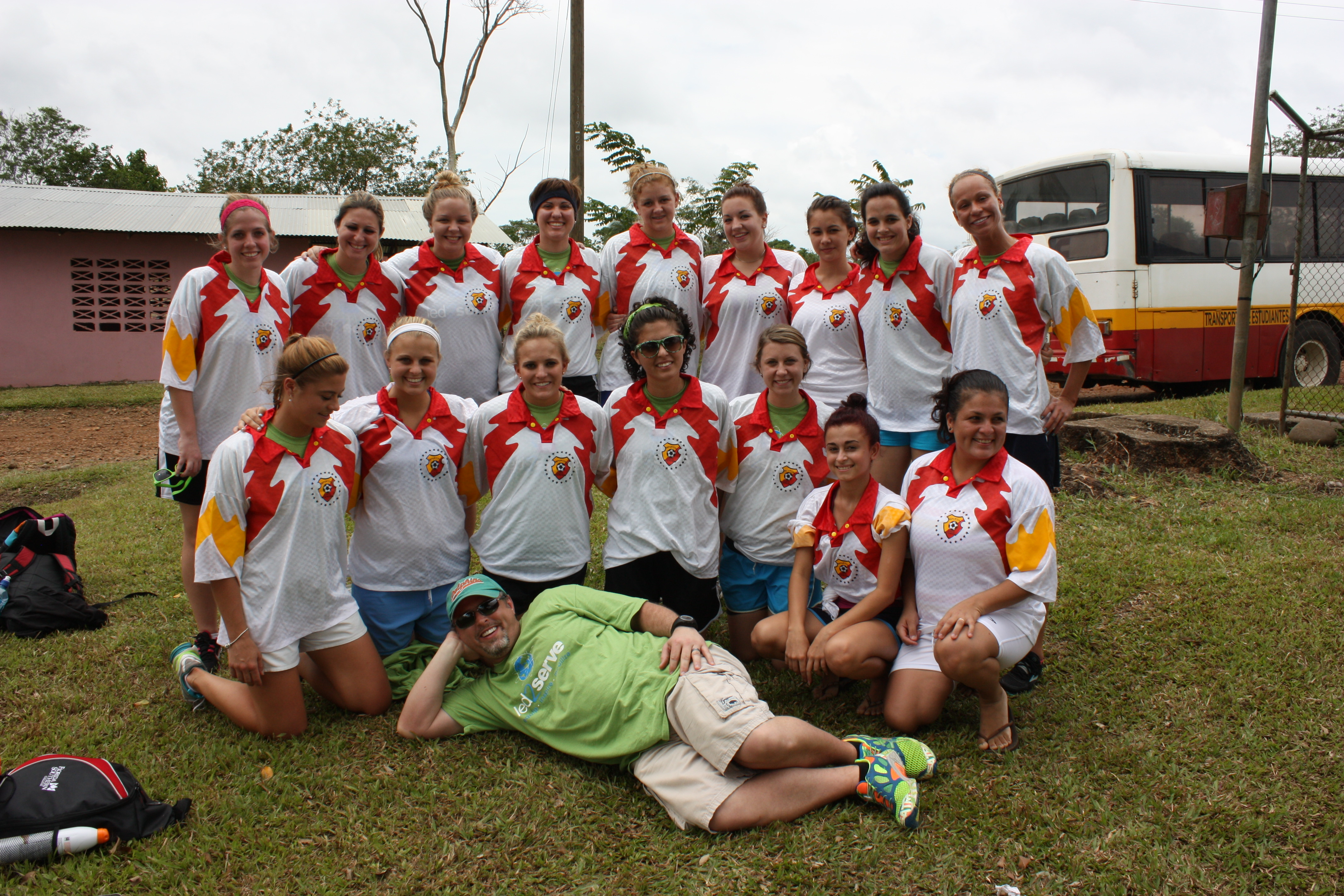 Mission team of 16 posing in front of a bus in matching jerseys