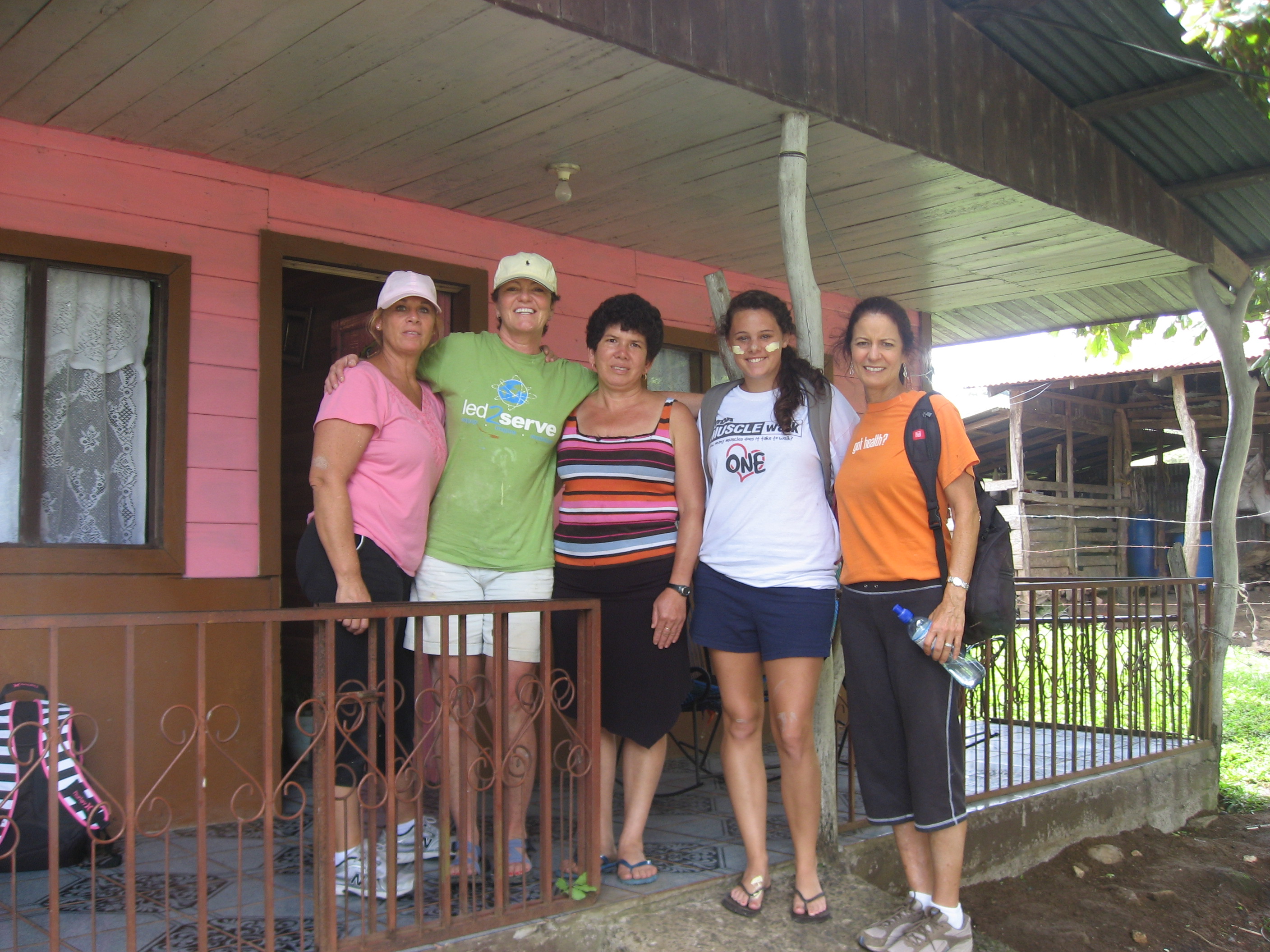 Five women volunteers posing together on a porch