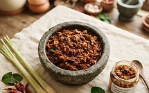 Homemade Tom Yum paste in a small bowl surrounded by fresh aromatics