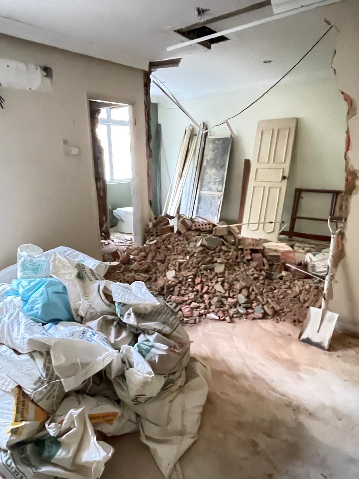 Demolition debris bags and broken brick wall after hacking works in a Singapore flat