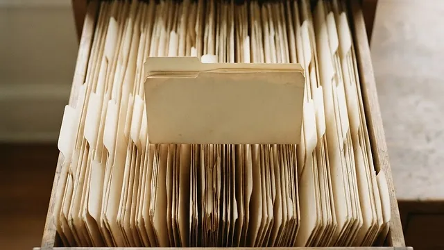 A drawer of card folders seen from above with one folder raised.