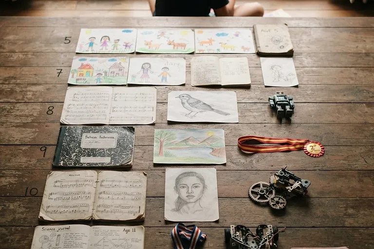 Six years of one child's work, laid out: notebooks, medals, robot parts, drawings.