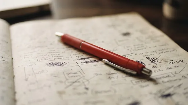A red pen resting on a marked page.