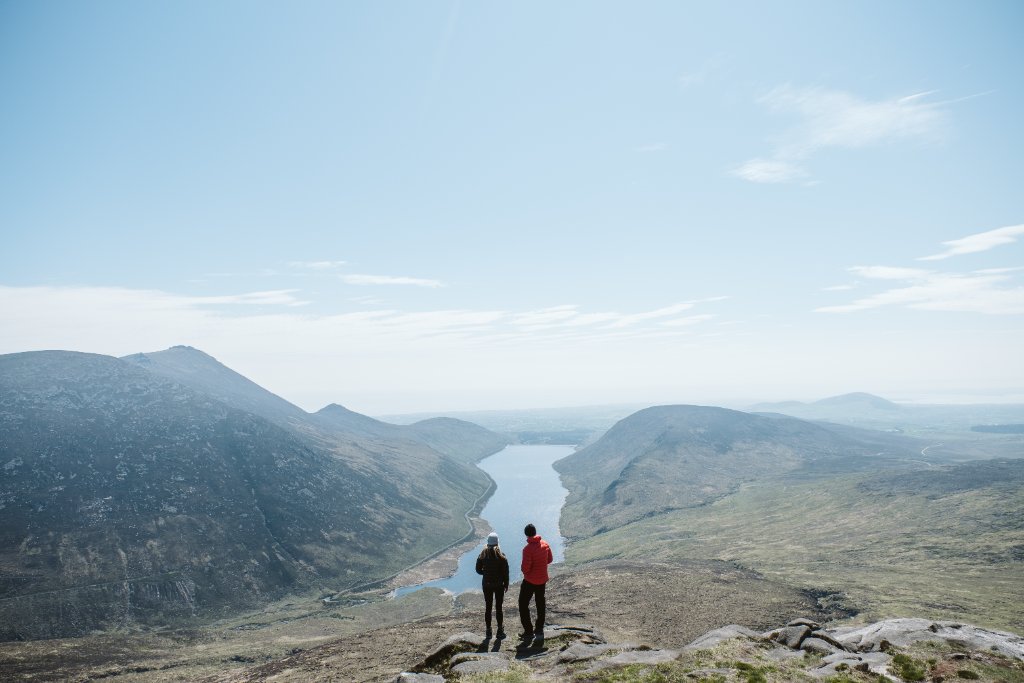 Two people overlooking a mountain valley and reservoir