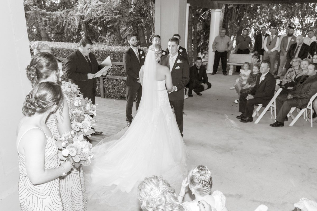A wedding ceremony under the covered rotunda at Hunter Valley Gardens, the bride and groom at the altar with guests seated beside them