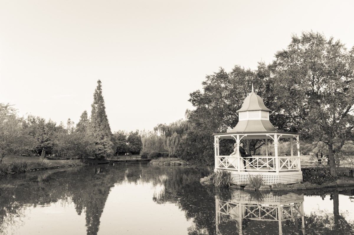 A couple in the white gazebo on the lake at Hunter Valley Gardens, the water and themed gardens reflected around them